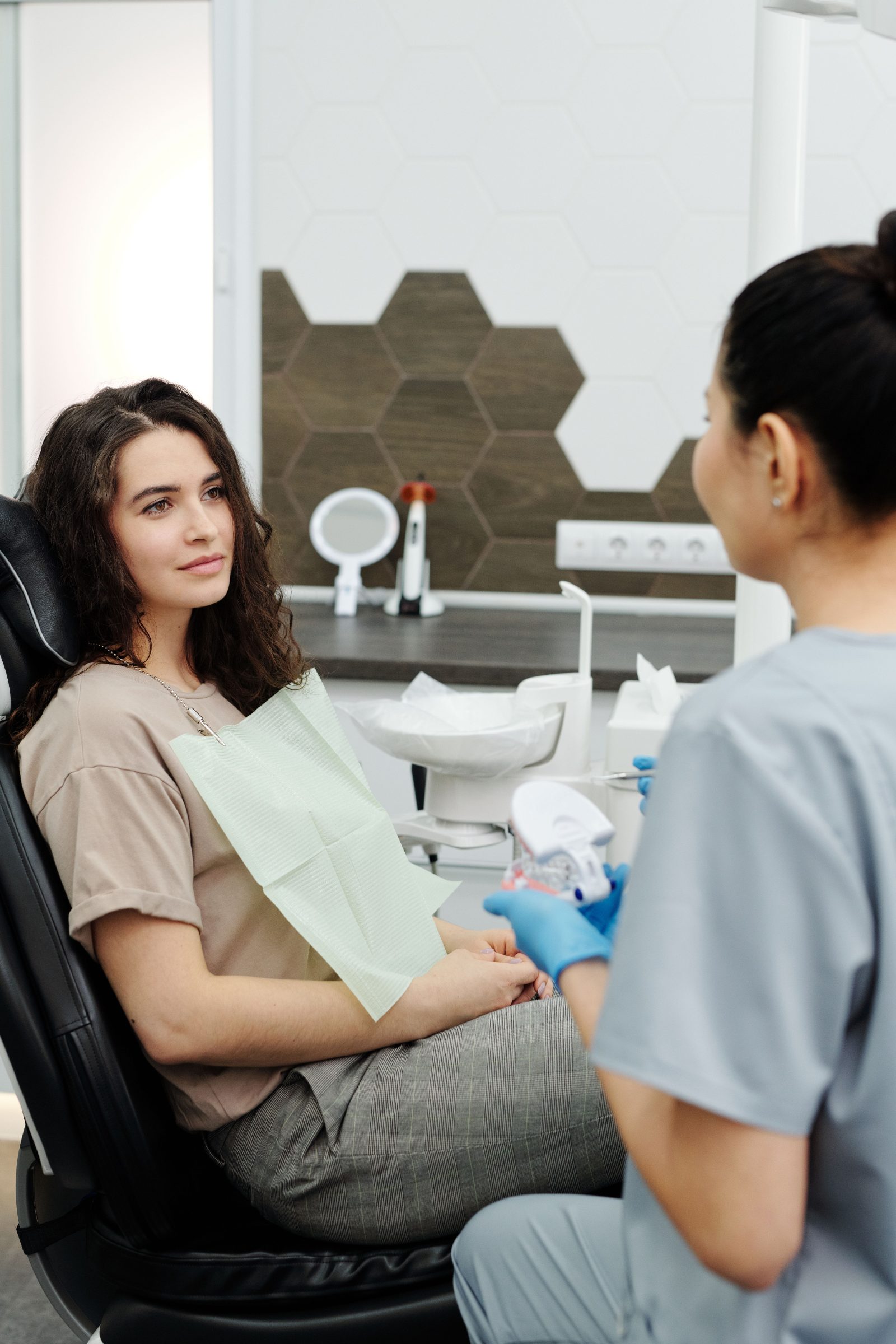 A dentist and patient looking together at a model of a dental crown beside the chair